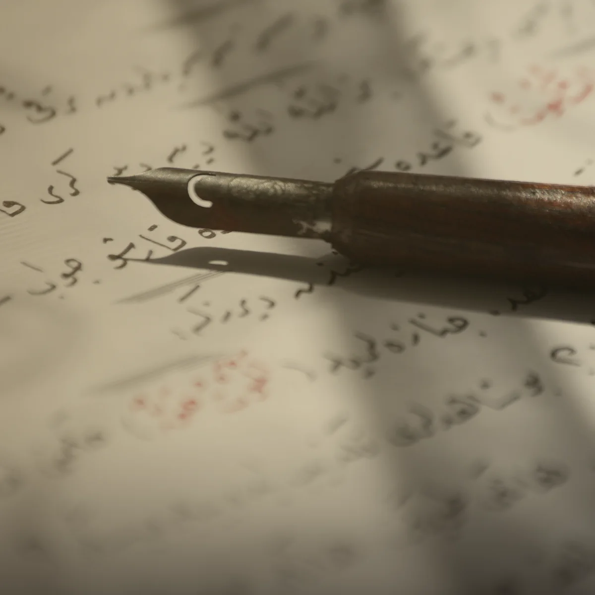 Pluma de caligrafía antigua sobre un texto en árabe