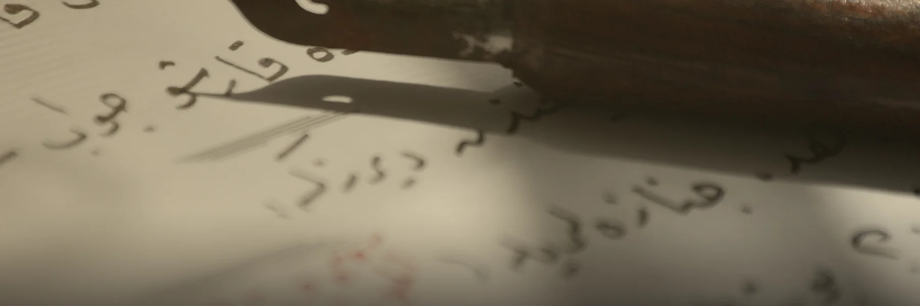 Pluma de caligrafía antigua sobre un texto en árabe