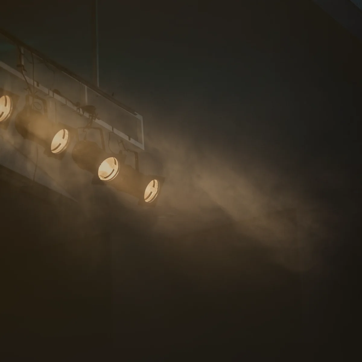 Focos de escenario encendidos entre el humo de un concierto